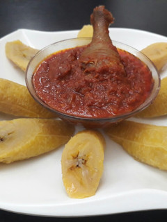 A picture of Boiled plantain with tomato sauce and fried chicken.