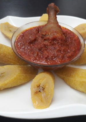 A picture of Boiled plantain with tomato sauce and fried chicken.