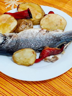 Una foto de Lubina al horno con papas y pimiento