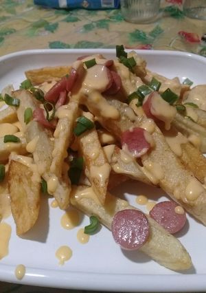 Una foto de Papas fritas con queso cheddar