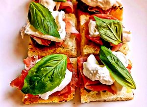 Foto di Crostini di Pizza con Patè di Olive Taggiasche Stracciatella Prosciutto Crudo e Basilico
