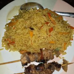 A picture of Fried carrot rice with chicken kebab.