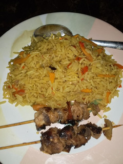 A picture of Fried carrot rice with chicken kebab.