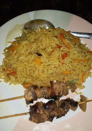 A picture of Fried carrot rice with chicken kebab.