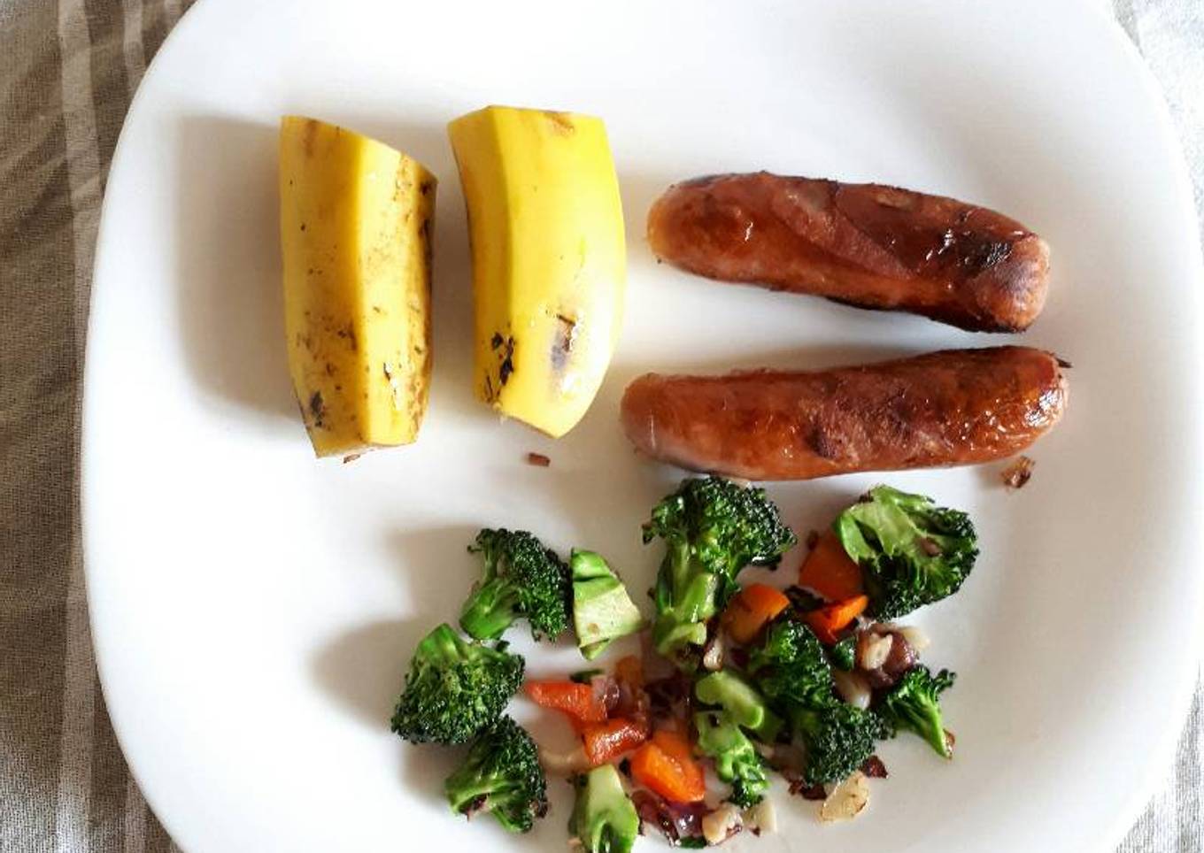 Sausages served with brocolli and fruit
