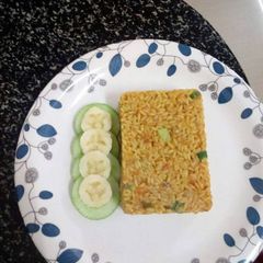 A picture of Jollof rice served with cucumber and banana.