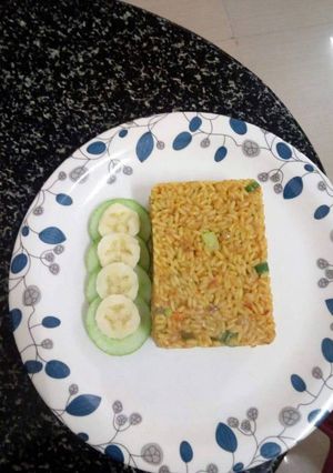 A picture of Jollof rice served with cucumber and banana.
