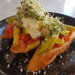 A picture of Avomato Bruschetta With Poached Egg And Alfalfa.