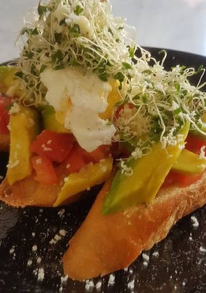 A picture of Avomato Bruschetta With Poached Egg And Alfalfa.