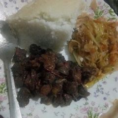 A picture of Fried beef served with ugali and fried cabbage.