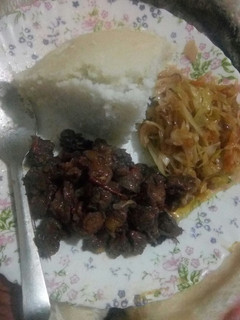 A picture of Fried beef served with ugali and fried cabbage.