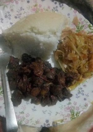 A picture of Fried beef served with ugali and fried cabbage.