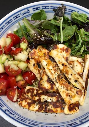 Une photo de Bouddha bowl tomates -oignon-concombre sur son lit de boulgour et halloumi