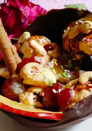 A picture of Chocolate bowl with fruits and nuts and Icecream.