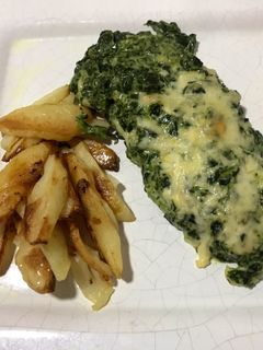 Una foto de Mila de pollo con salsa blanca y espinaca acompañado de papas al horno