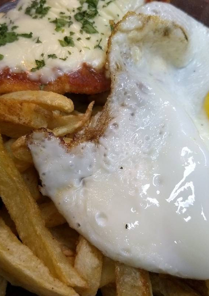 Una foto de Milanesas a la napolitana con papas fritas y huevos fritos