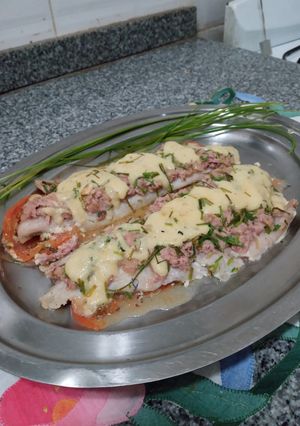 Una foto de Merluza al atún y queso azul, sobre base de tomates al tomillo