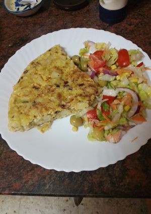 Una foto de Tortilla de papas con cebolla y puerro sofrito y ensalada