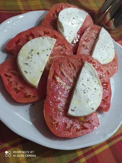 Una foto de Tomates de El Bierzo con albahaca y queso fresco