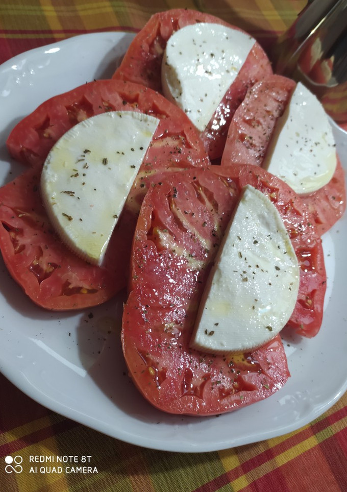 Una foto de Tomates de El Bierzo con albahaca y queso fresco