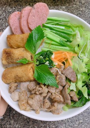 A picture of Vietnamese Noodle Bowl with Crispy Spring Rolls and Stir-Fried Pork.