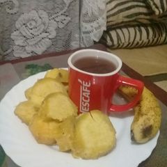 A picture of Boiled sweet potatoes, banana n a cup of hot Nescafe.