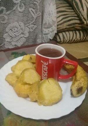 A picture of Boiled sweet potatoes, banana n a cup of hot Nescafe.