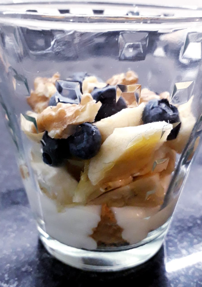 Una foto de Postre en vaso de banana, coco y arándanos