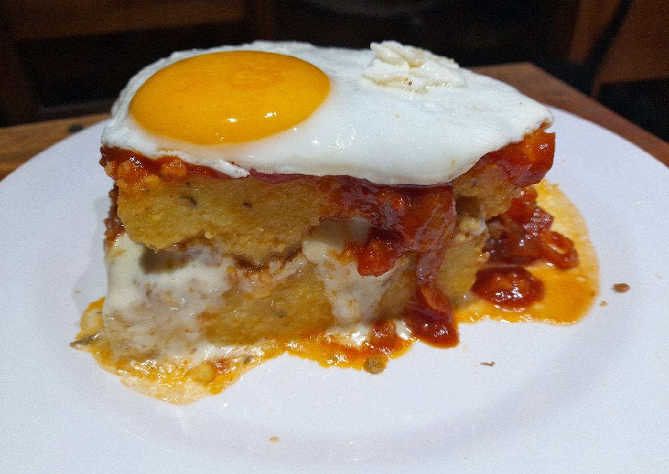 Pastel de polenta con bolognesa, queso, tuco y a caballo