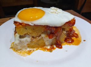 Una foto de Pastel de polenta con bolognesa, queso, tuco y a caballo