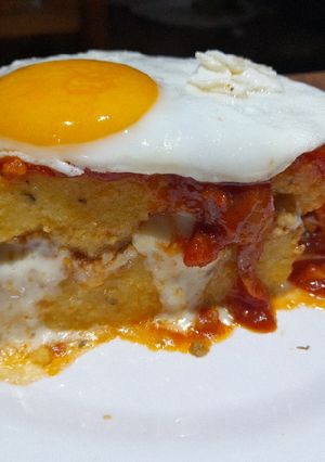 Una foto de Pastel de polenta con bolognesa, queso, tuco y a caballo