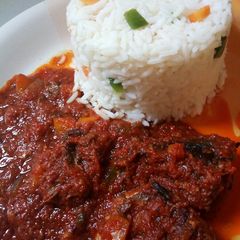 A picture of Garnished white rice and fish stew.