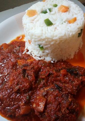 A picture of Garnished white rice and fish stew.