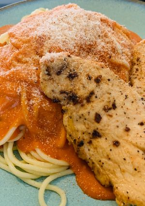 Una foto de Spaguettis en salsa rosada, queso parmesano y nuez moscada con pechuga de pollo