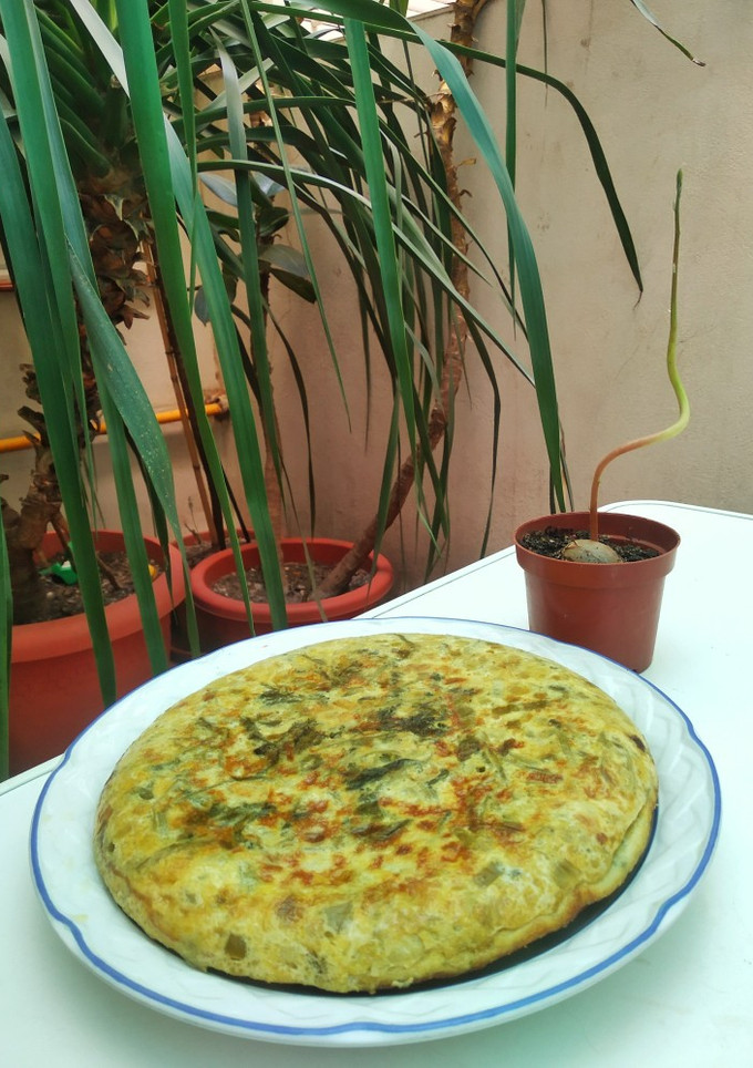 Una foto de Tortilla de cebolleta, pimiento verde y hojas de rabanito
