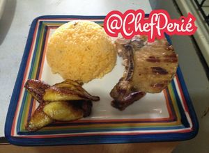 Una foto de Chuletas a la plancha con arroz amarillo con cebollas y ají acompañado de tajadas