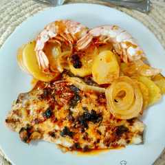 Foto di Dorada al horno con gambones, patata y cebolla