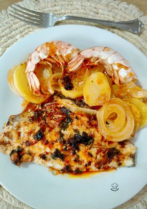 Una foto de Dorada al horno con gambones, patata y cebolla