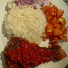 A picture of Pepper fried fish with boiled rice and sliced tomatoes.