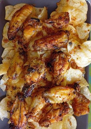 Una foto de Alitas de pollo al limón con cebolla caramelizada en Airfryer sobre cama de patatas chips