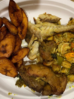 A picture of Jollof rice with fried plantain,fried chicken and smoked fish.