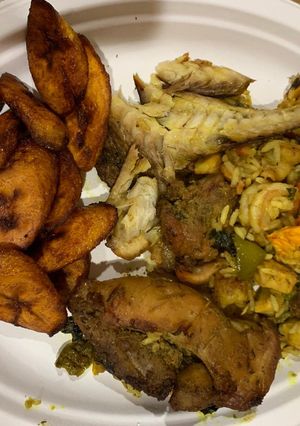 A picture of Jollof rice with fried plantain,fried chicken and smoked fish.