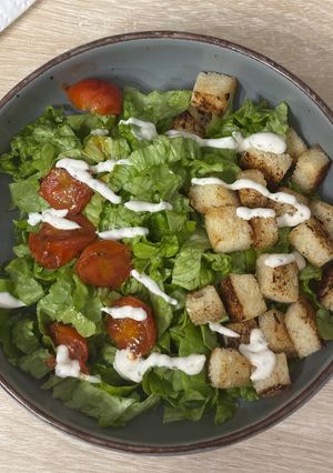 Una foto de Ensalada con tomates cherry, pan crujiente y salsa César
