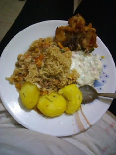 A picture of Rosemary potatoes with rice, chicken and sauce.