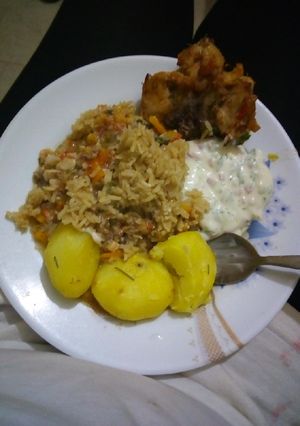 A picture of Rosemary potatoes with rice, chicken and sauce.