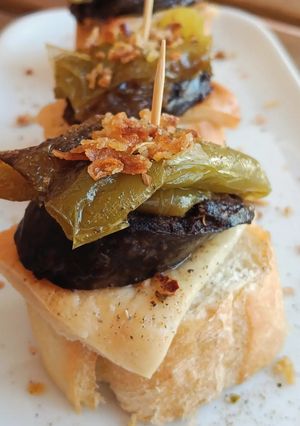 Una foto de Pincho de morcilla y pimiento frito con queso de romero fundido