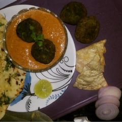 A picture of Palak kofta in red Gravy with Garlic naan.
