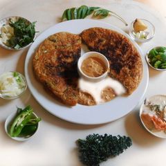 A picture of Nutritious, aromatic, spicy corn flour Uthappam wih green leaves.