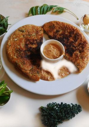 A picture of Nutritious, aromatic, spicy corn flour Uthappam wih green leaves.