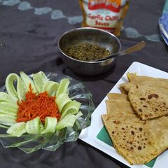 A picture of Aloo paratha with palak and achar.